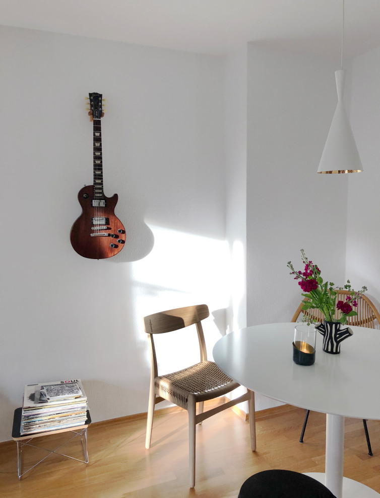 Aménagement d'une petite salle à manger ouverte sur le salon contemporaine avec un mur blanc, parquet clair, aucune cheminée et un sol marron.