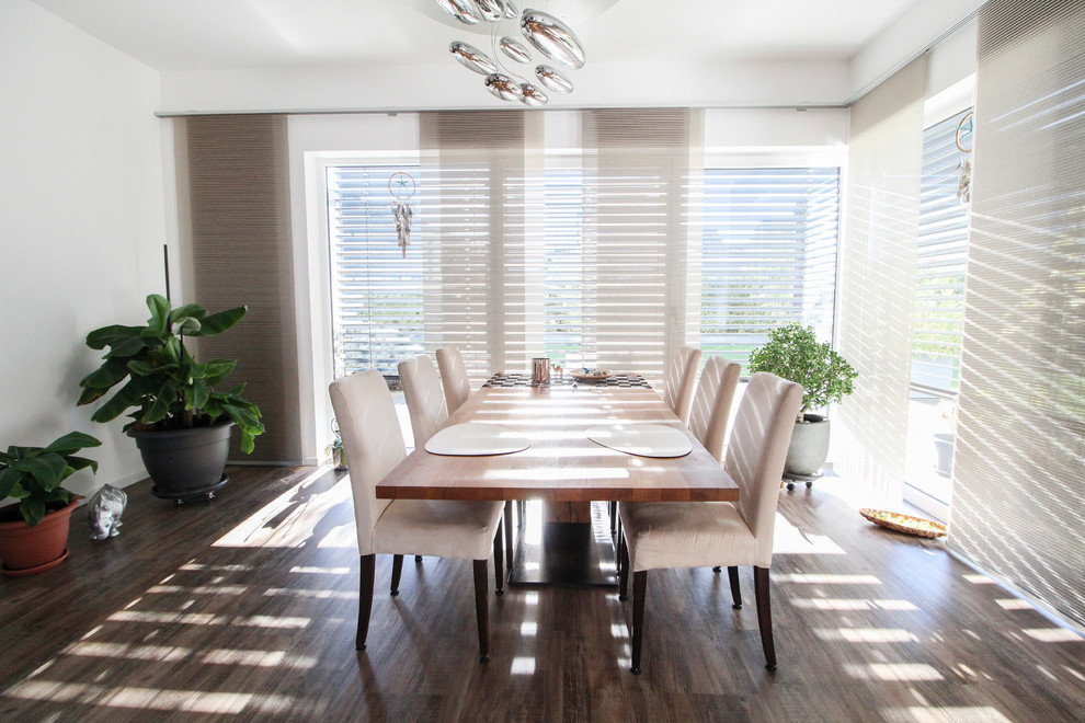 Cette photo montre une salle à manger tendance fermée avec un mur blanc, parquet foncé et un sol marron.