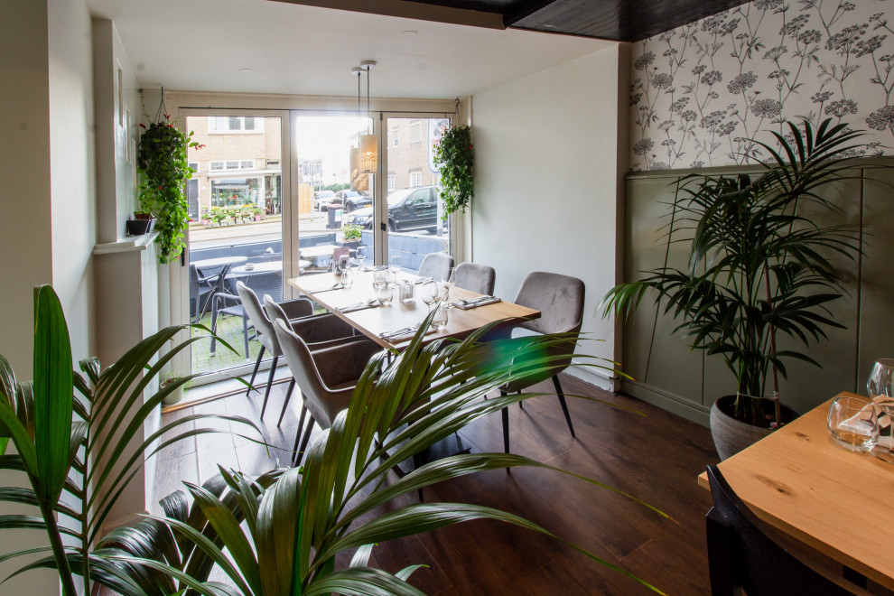 Foto di una sala da pranzo aperta verso il soggiorno minimal di medie dimensioni con pareti verdi, pavimento in laminato, pavimento marrone e boiserie