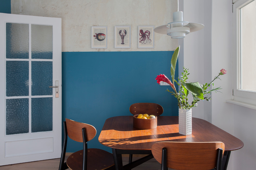Foto di una sala da pranzo aperta verso la cucina minimalista con pareti blu, pavimento in legno massello medio e pavimento marrone