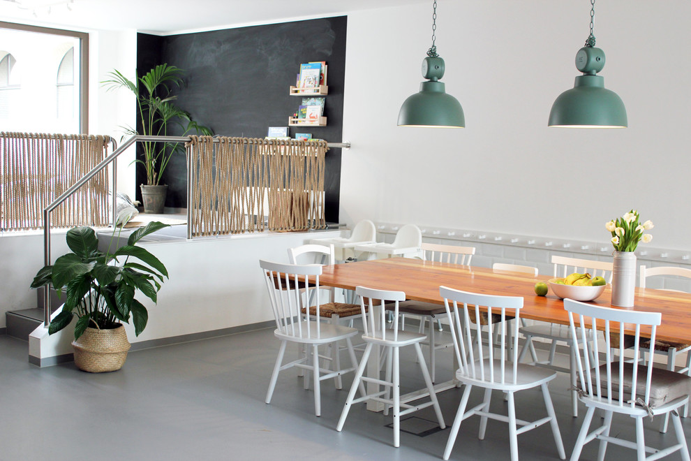 Foto di una sala da pranzo aperta verso il soggiorno minimal di medie dimensioni con pareti bianche, pavimento in cemento, nessun camino e pavimento grigio