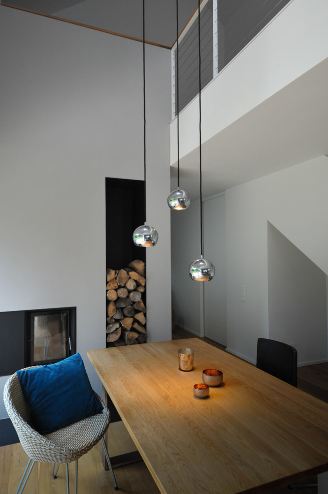 Offenes, Mittelgroßes Modernes Esszimmer mit grauer Wandfarbe, braunem Holzboden, Tunnelkamin, verputzter Kaminumrandung und braunem Boden in Nürnberg