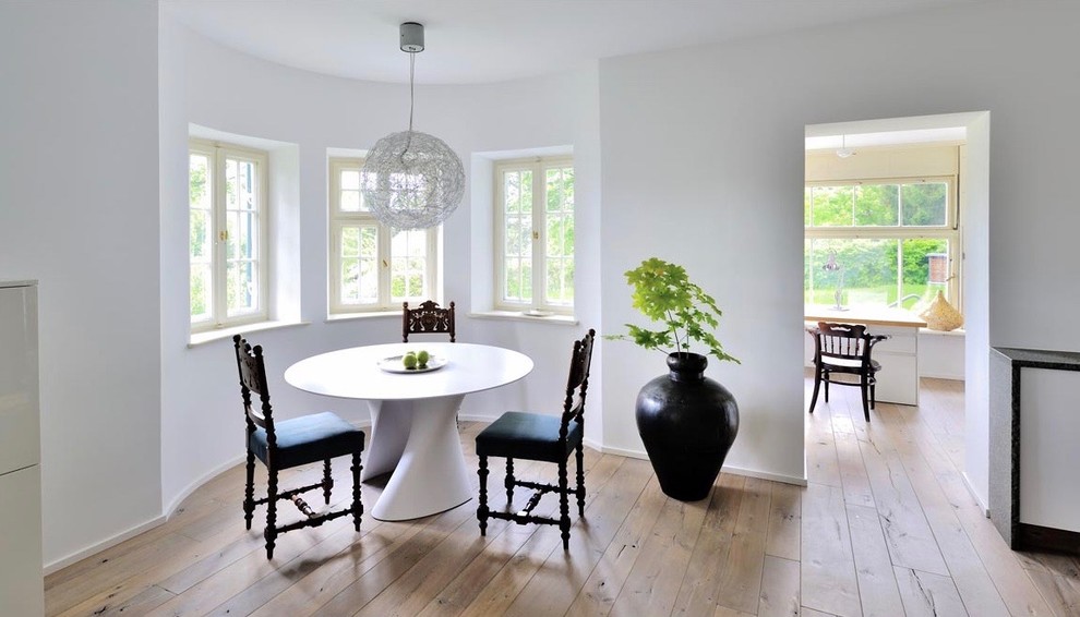 Exemple d'une grande salle à manger éclectique avec un mur blanc, un sol en bois brun, une cheminée standard, un manteau de cheminée en plâtre et un sol marron.