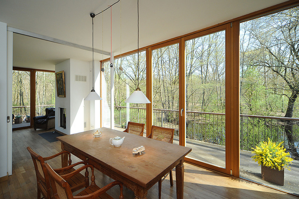 Imagen de comedor contemporáneo con paredes blancas y suelo de madera en tonos medios