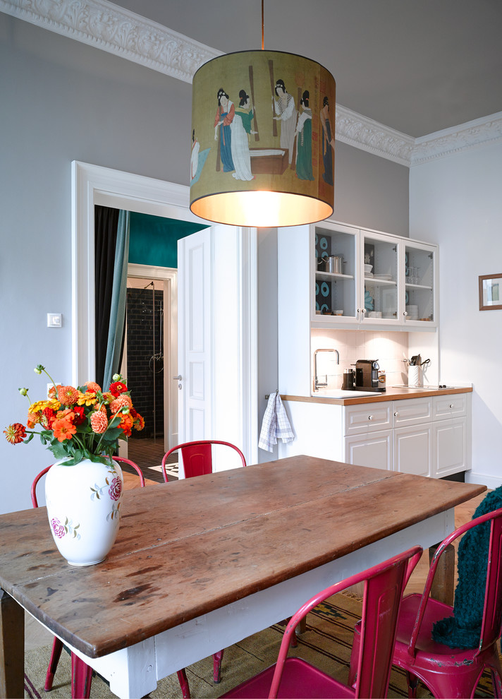 Exemple d'une salle à manger ouverte sur la cuisine éclectique de taille moyenne avec un mur gris et un sol en bois brun.