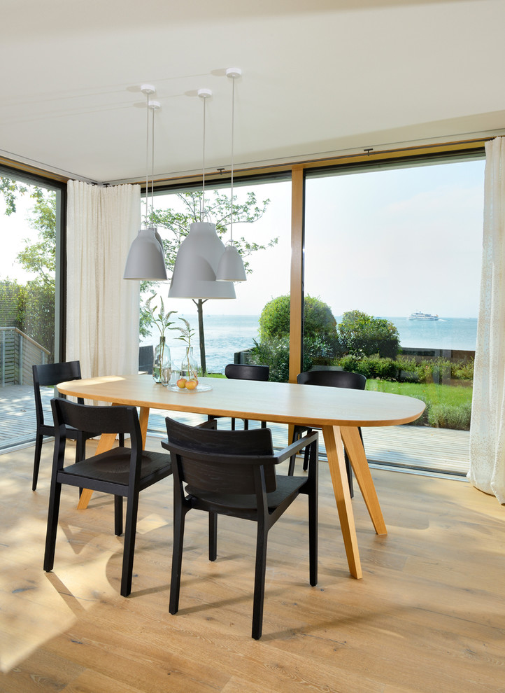 Immagine di una sala da pranzo aperta verso il soggiorno design con parquet chiaro