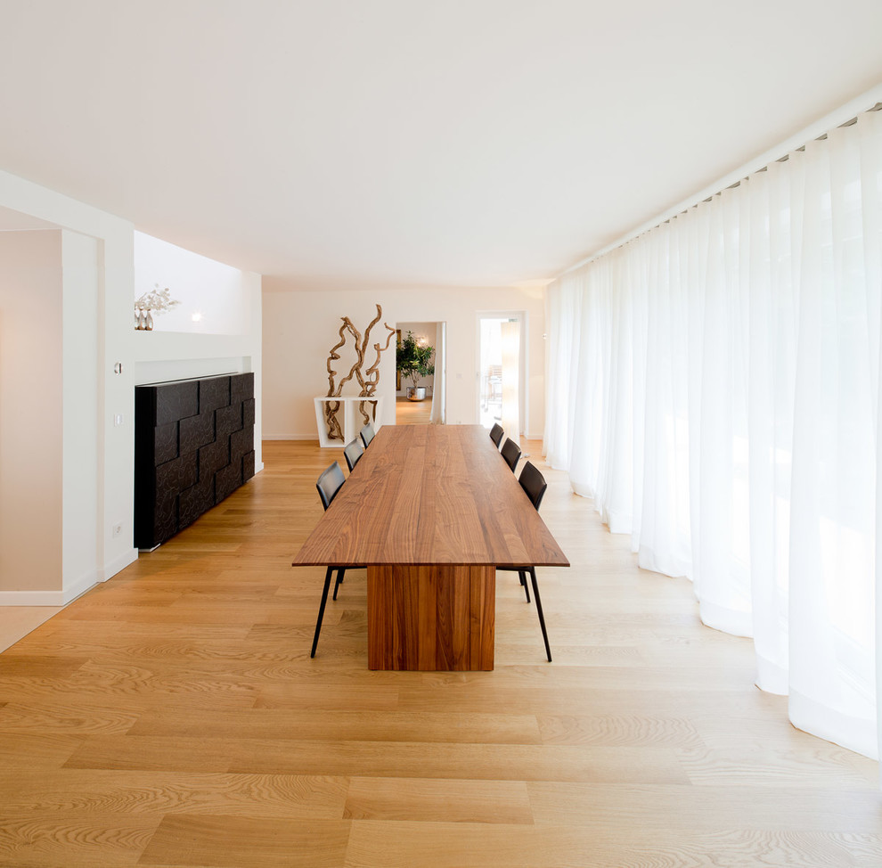 Exemple d'une grande salle à manger ouverte sur le salon tendance avec un mur blanc et un sol en bois brun.
