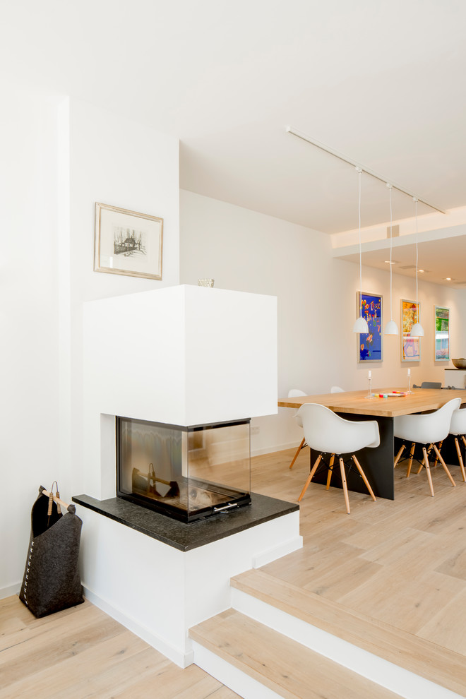 デュッセルドルフにある広いコンテンポラリースタイルのおしゃれなLDK (白い壁、無垢フローリング、横長型暖炉、漆喰の暖炉まわり、ベージュの床) の写真