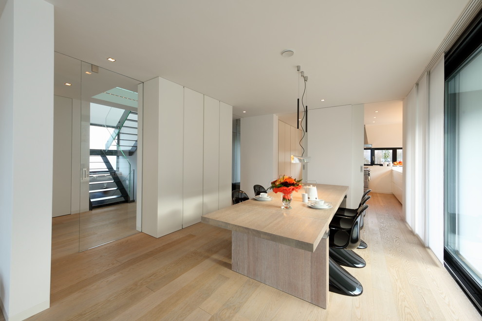 Photo of an expansive contemporary open plan dining room in Munich with white walls and light hardwood flooring.