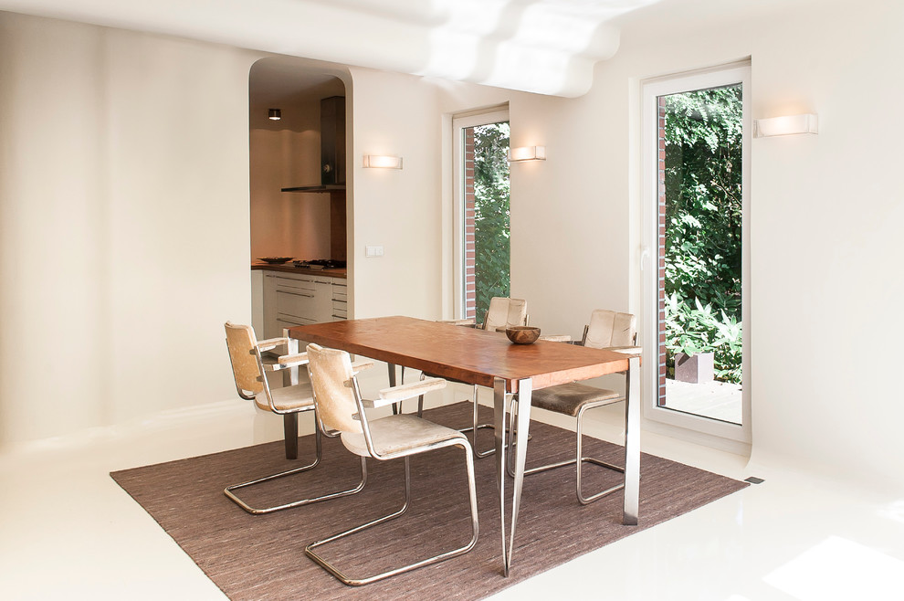 This is an example of a medium sized bohemian open plan dining room in Hamburg with white walls and concrete flooring.