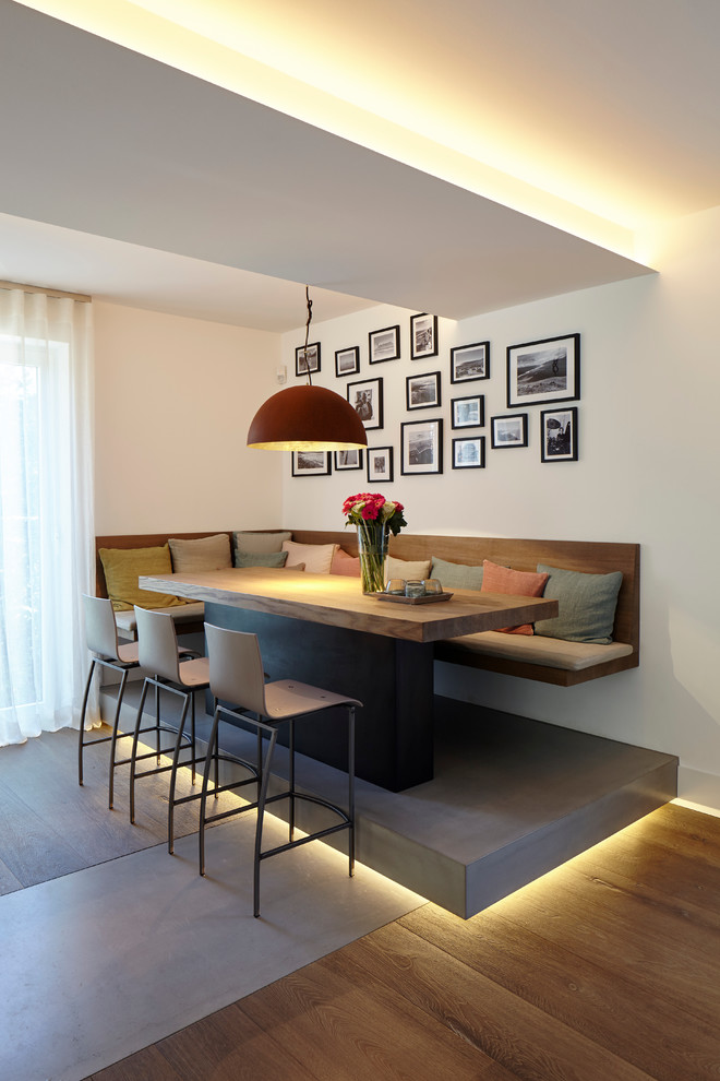 Idée de décoration pour une salle à manger design de taille moyenne avec un mur blanc et un sol en bois brun.