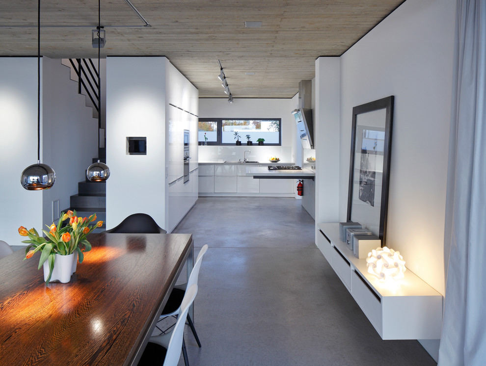 Idee per una grande sala da pranzo aperta verso la cucina minimal con pareti bianche, pavimento in cemento e nessun camino