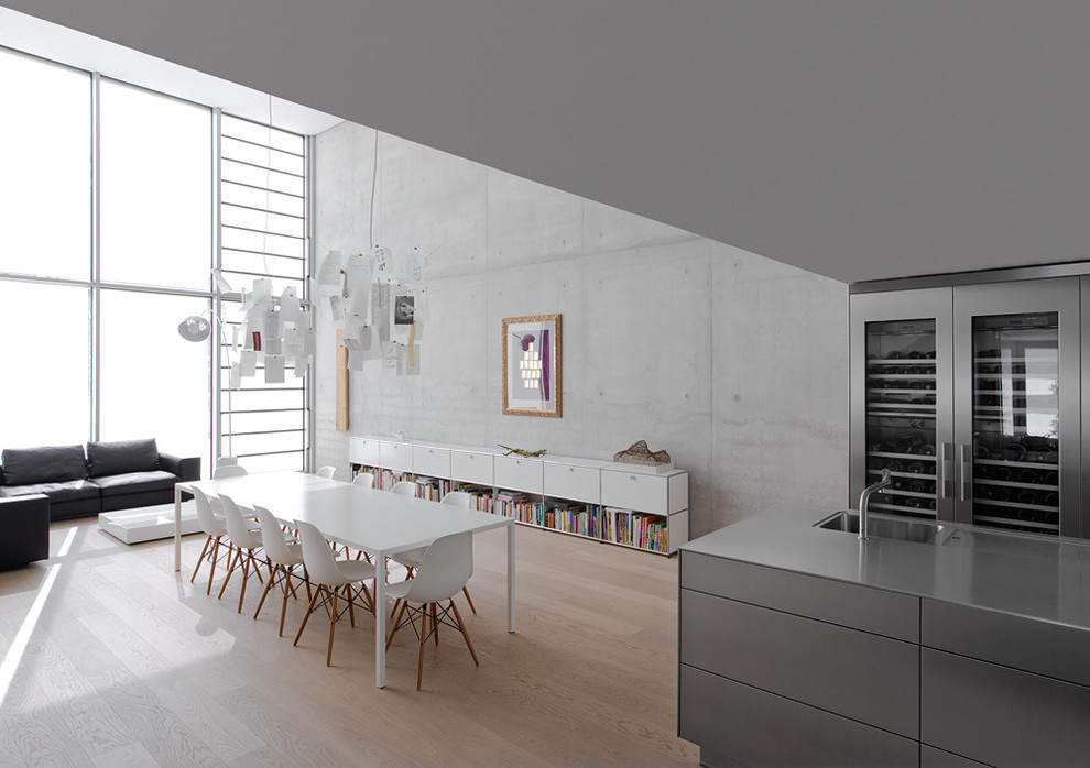 Réalisation d'une grande salle à manger ouverte sur la cuisine design avec un mur gris et parquet clair.