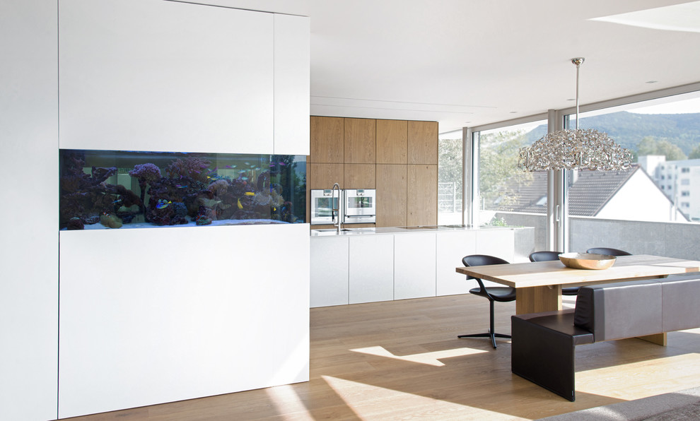 Ispirazione per una grande sala da pranzo aperta verso la cucina minimalista con pareti bianche e parquet chiaro