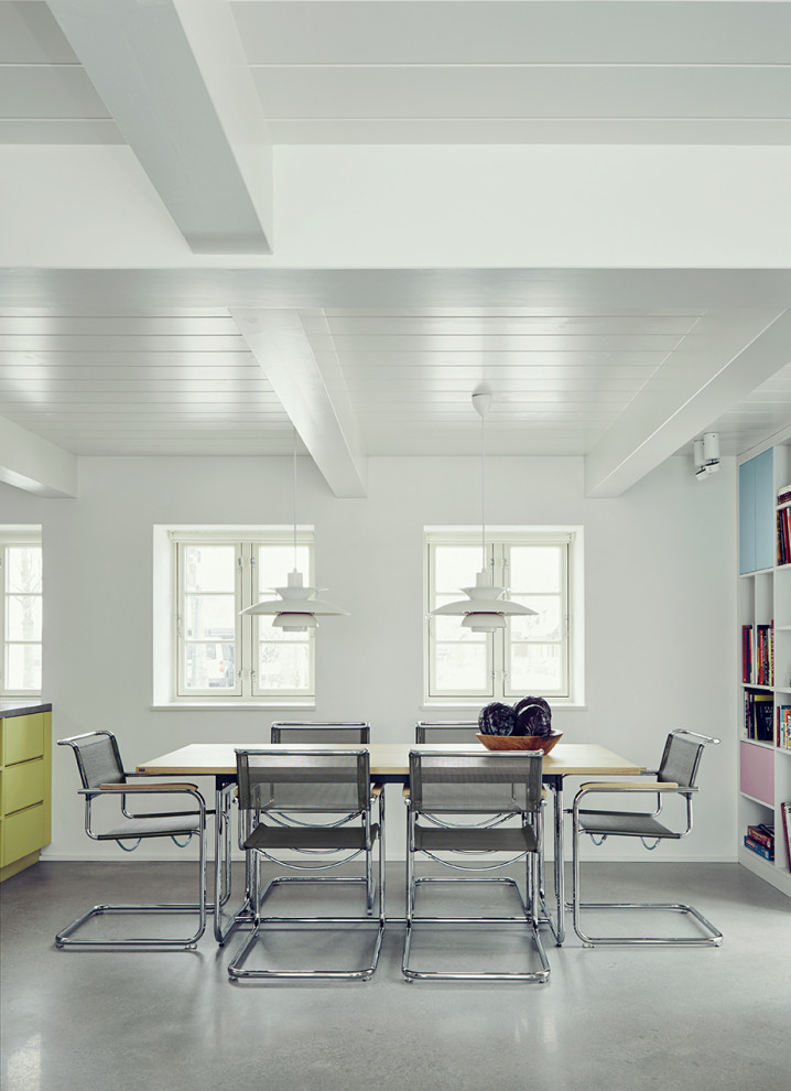 Foto di una sala da pranzo aperta verso il soggiorno minimal con pareti bianche, pavimento in cemento, pavimento grigio, travi a vista e soffitto in perlinato