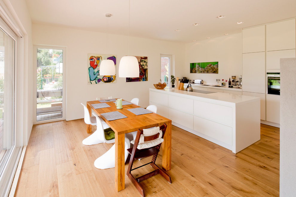 Immagine di una sala da pranzo aperta verso la cucina nordica di medie dimensioni con pareti bianche, pavimento in legno massello medio e nessun camino