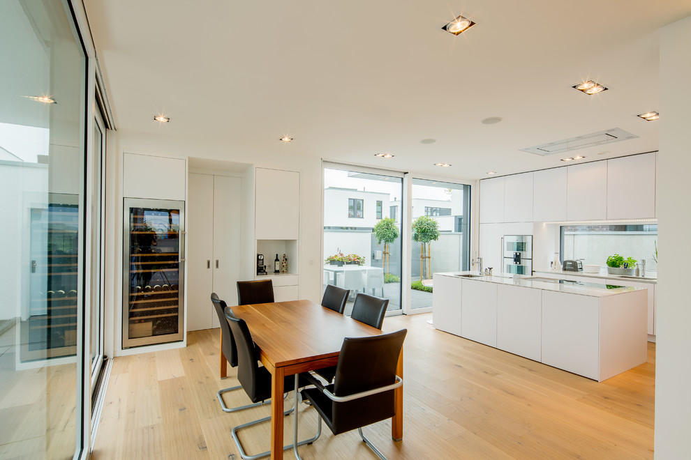 Große Moderne Wohnküche ohne Kamin mit braunem Holzboden, braunem Boden und weißer Wandfarbe in Düsseldorf