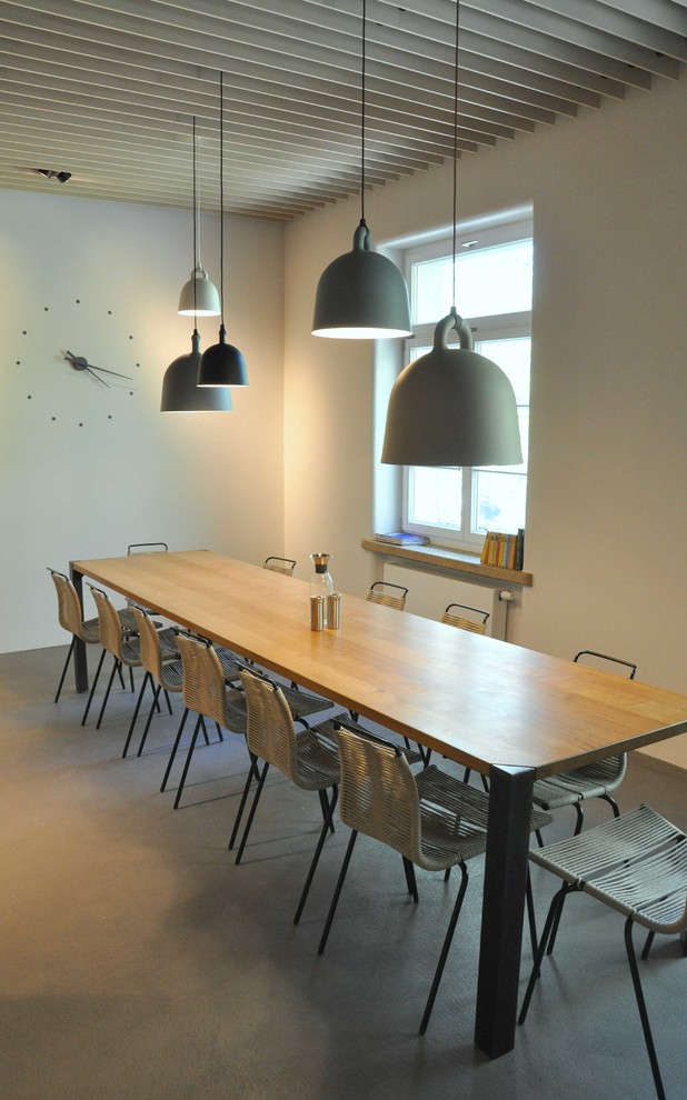 Foto de comedor escandinavo de tamaño medio abierto sin chimenea con paredes blancas, suelo de cemento y suelo gris