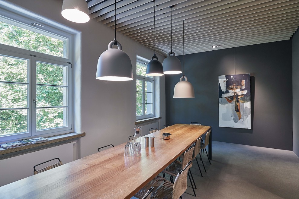 Cette photo montre une grande salle à manger tendance avec un mur gris, sol en béton ciré, un sol gris et aucune cheminée.