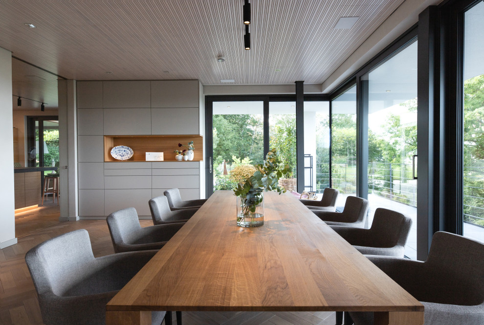 Foto di una grande sala da pranzo aperta verso il soggiorno industriale con pareti beige, parquet chiaro e pavimento beige