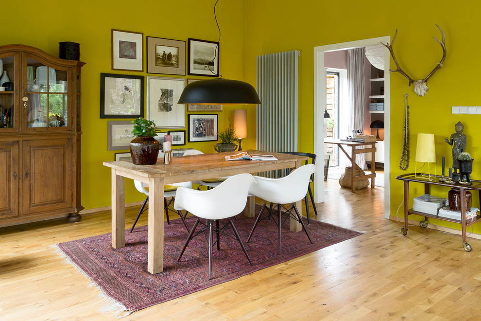 Bild på en mellanstor eklektisk matplats med öppen planlösning, med gula väggar och ljust trägolv