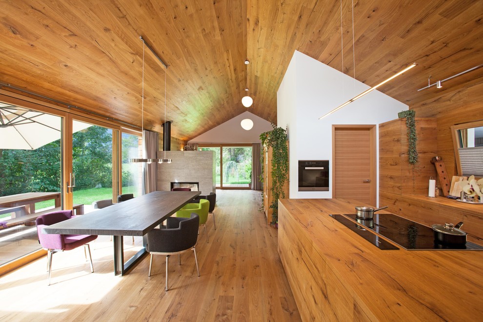 Ispirazione per una sala da pranzo aperta verso la cucina design con pavimento in legno massello medio e pareti bianche