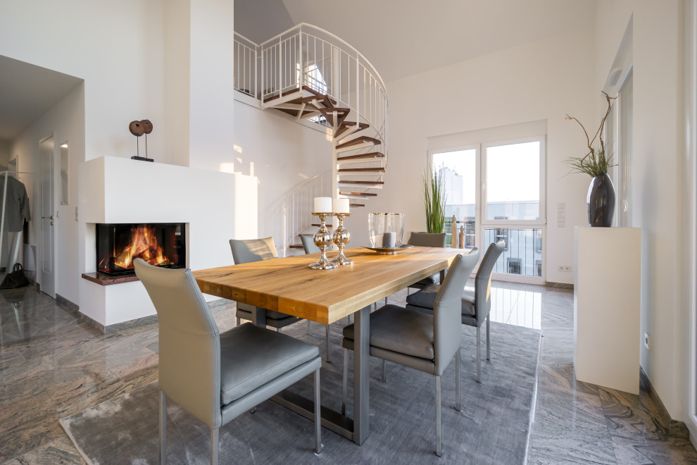 Photo of a contemporary open plan dining room in Other with white walls, a corner fireplace and grey floors.