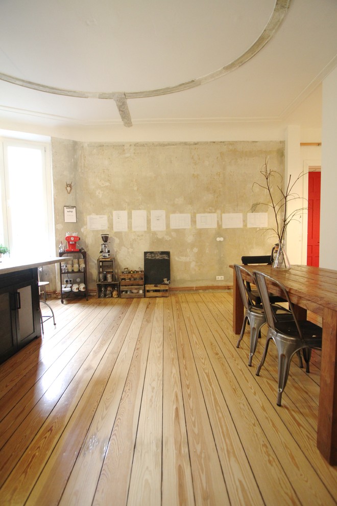 Immagine di una sala da pranzo aperta verso il soggiorno industriale con pavimento in legno massello medio, nessun camino e pareti bianche