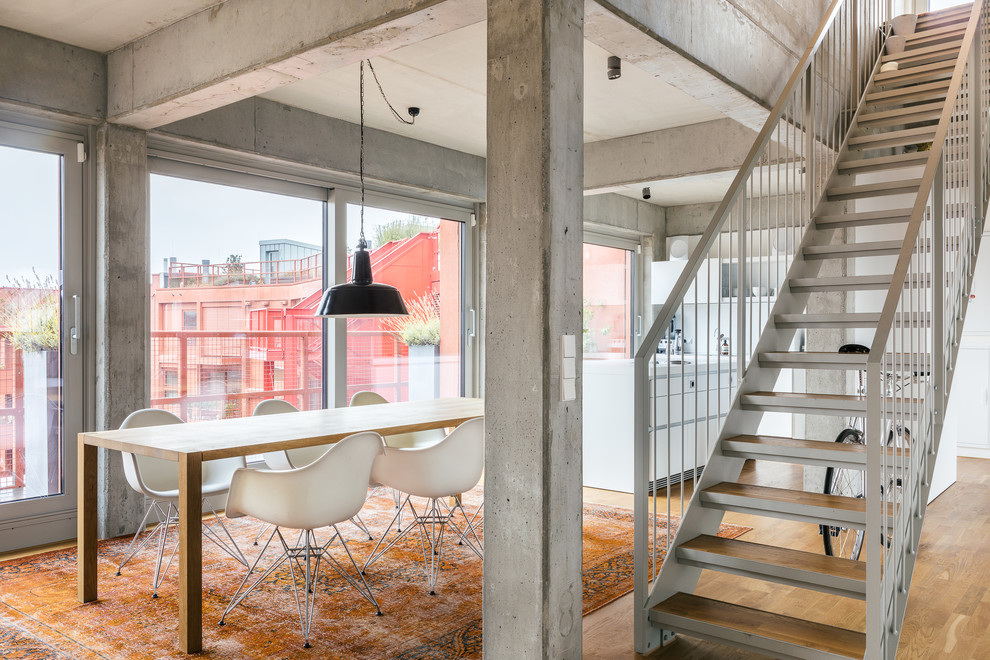 Diseño de comedor industrial abierto con paredes grises y suelo de madera en tonos medios