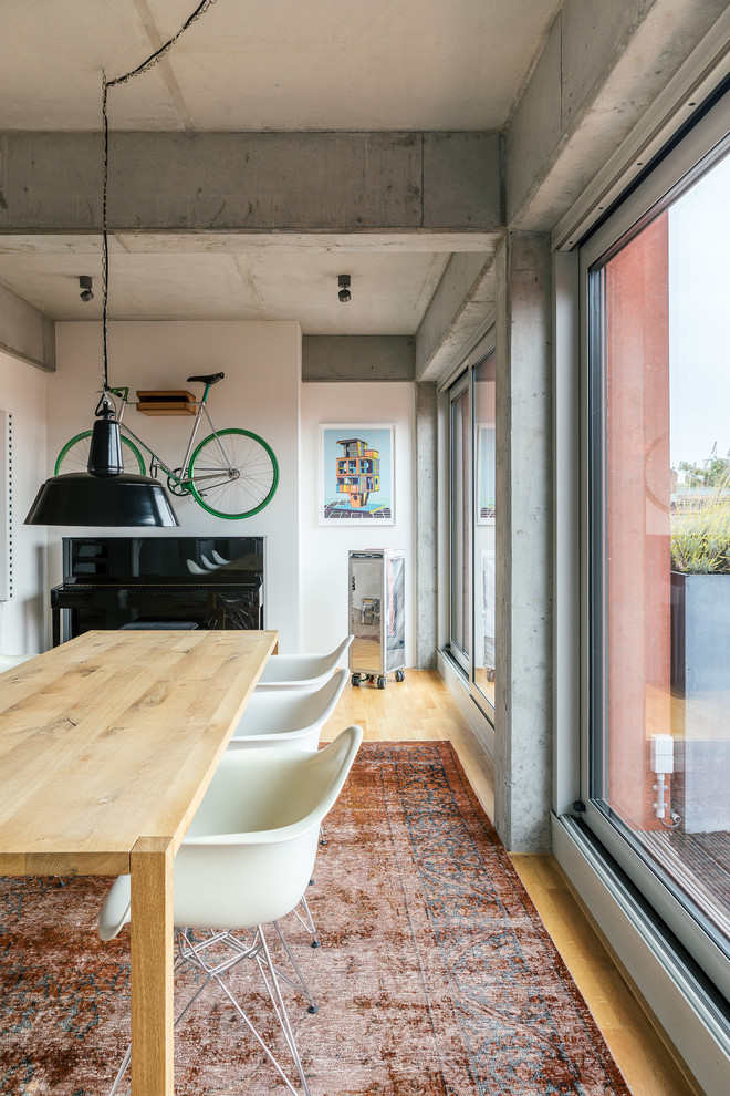 Ispirazione per una sala da pranzo aperta verso il soggiorno industriale con pareti grigie e pavimento in legno massello medio