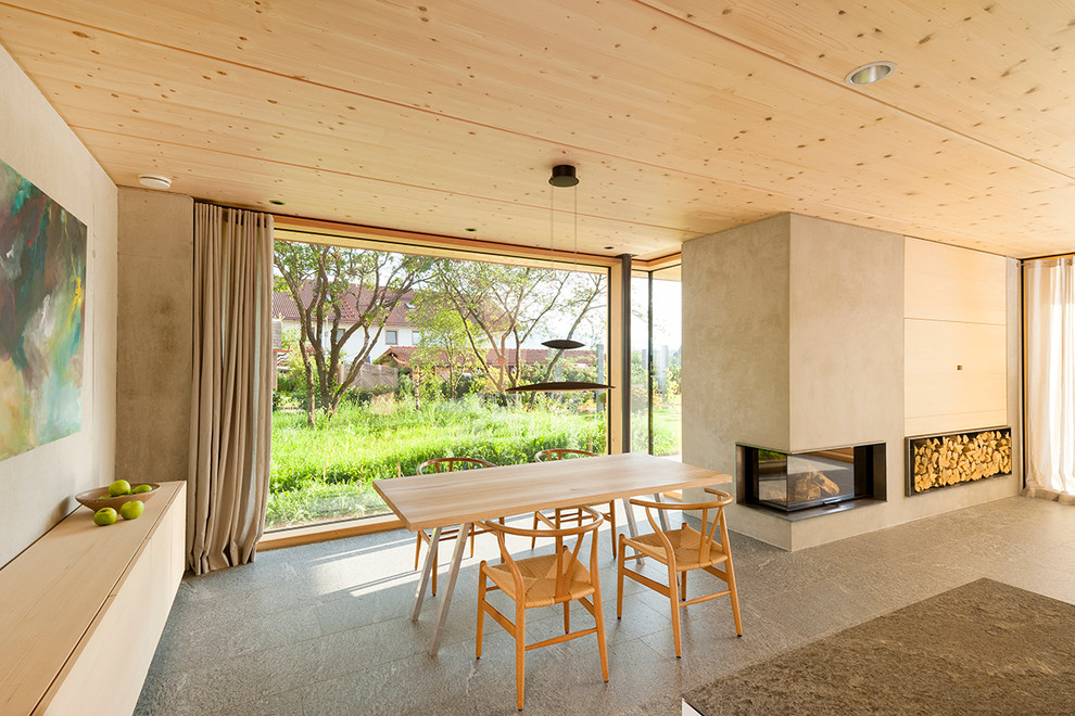 Inspiration pour une salle à manger ouverte sur le salon design avec un mur beige, un manteau de cheminée en plâtre et une cheminée standard.