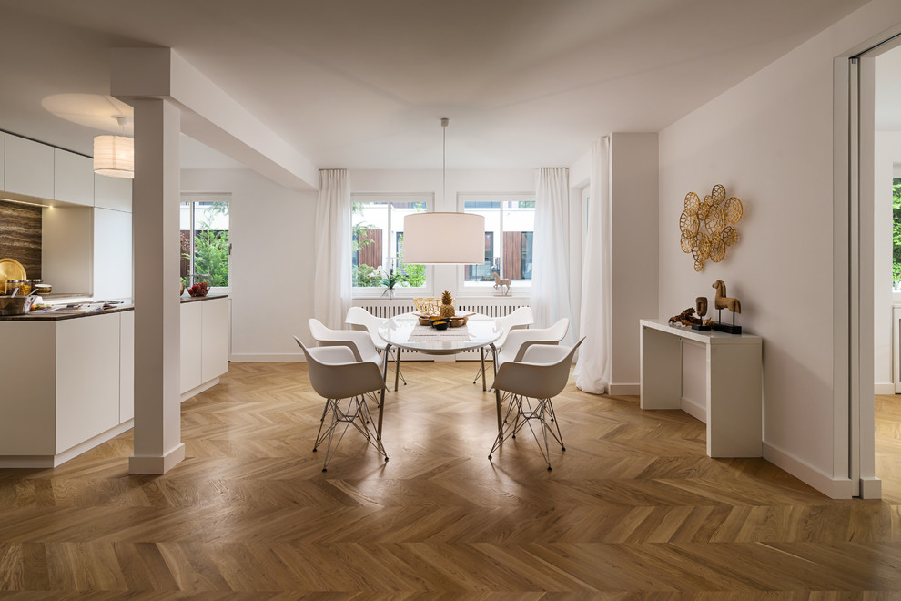 Immagine di una grande sala da pranzo aperta verso il soggiorno minimal con pareti bianche, pavimento in legno massello medio, nessun camino e pavimento marrone