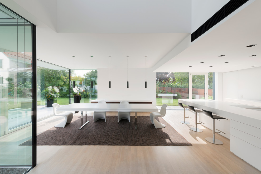 Inspiration pour une grande salle à manger ouverte sur la cuisine minimaliste avec un mur blanc et parquet clair.