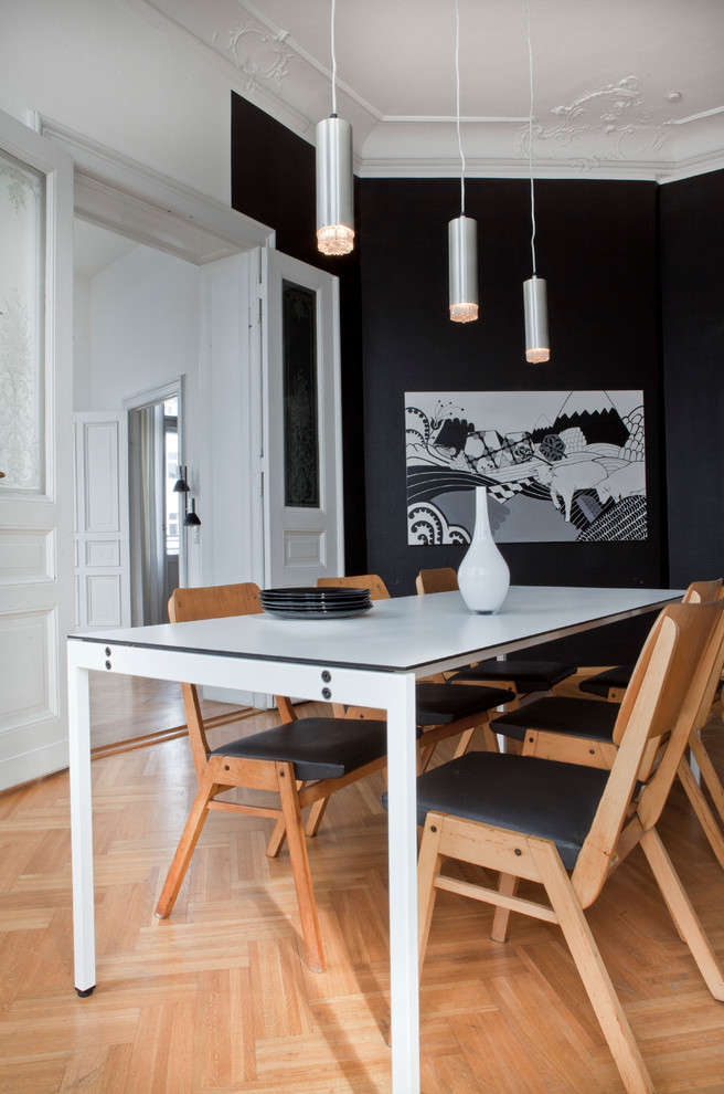 Imagen de comedor nórdico de tamaño medio cerrado con paredes negras y suelo de madera clara