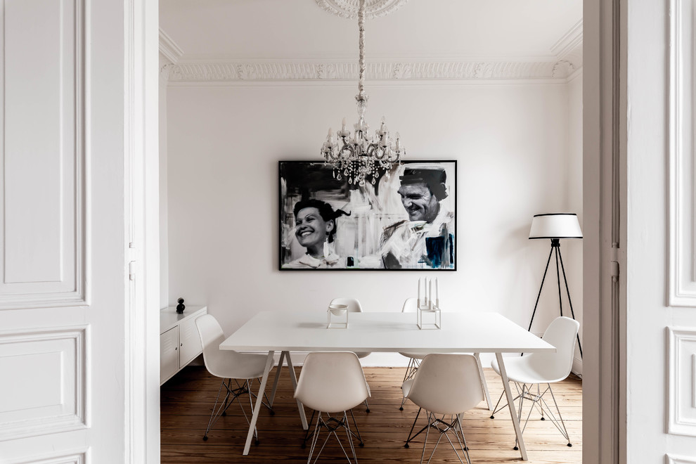Photo of a scandi enclosed dining room in Hamburg with white walls, medium hardwood flooring and brown floors.