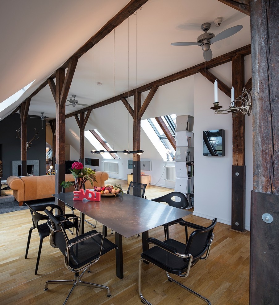 Example of a large mountain style medium tone wood floor and brown floor great room design in Hamburg with white walls, a standard fireplace and a concrete fireplace