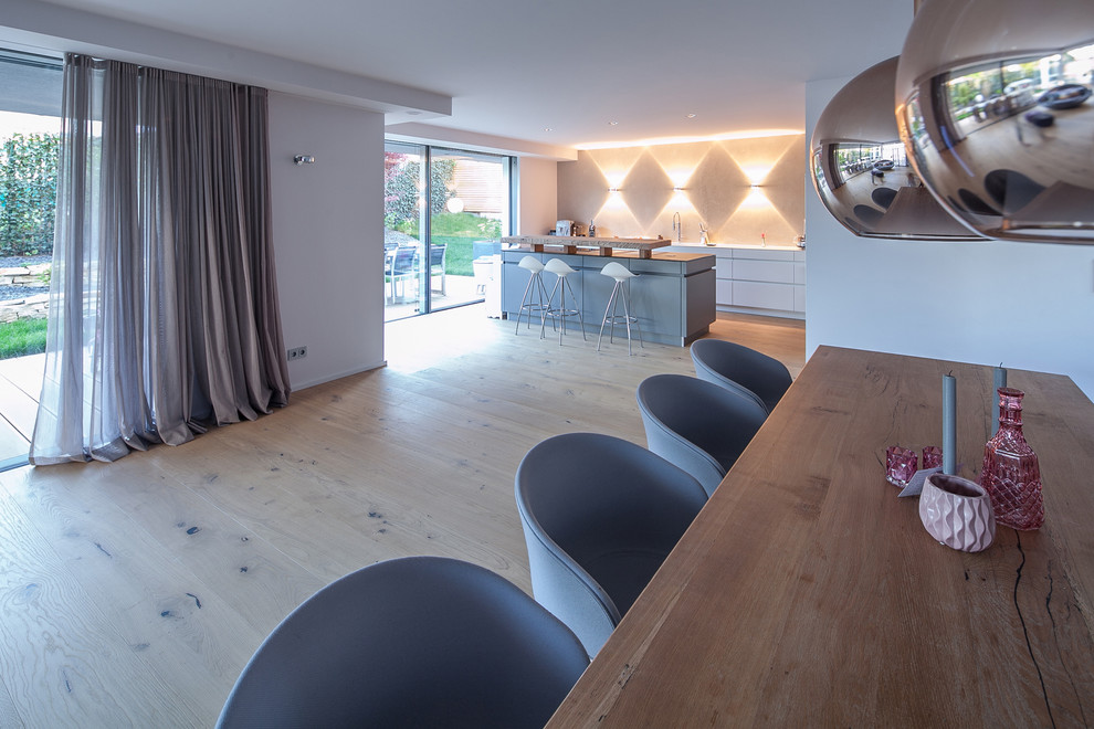Idee per una grande sala da pranzo aperta verso il soggiorno moderna con pareti bianche, parquet chiaro e pavimento marrone