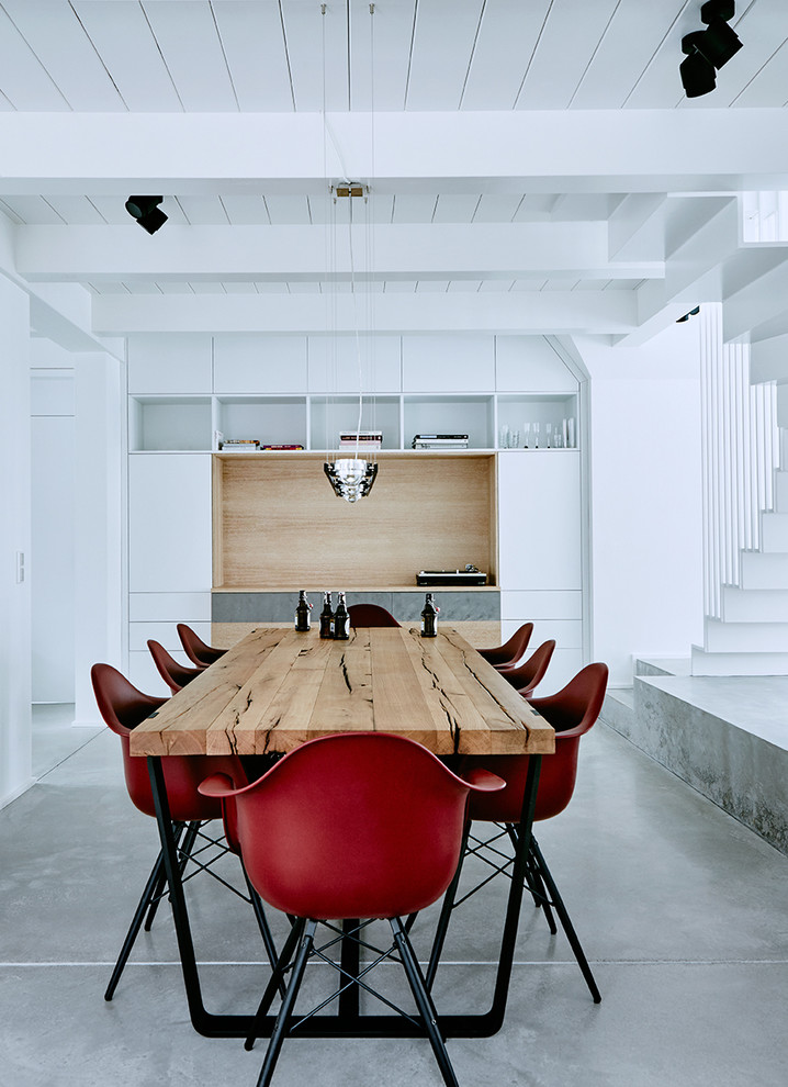 Immagine di una sala da pranzo aperta verso il soggiorno contemporanea di medie dimensioni con pareti bianche, pavimento in cemento e nessun camino