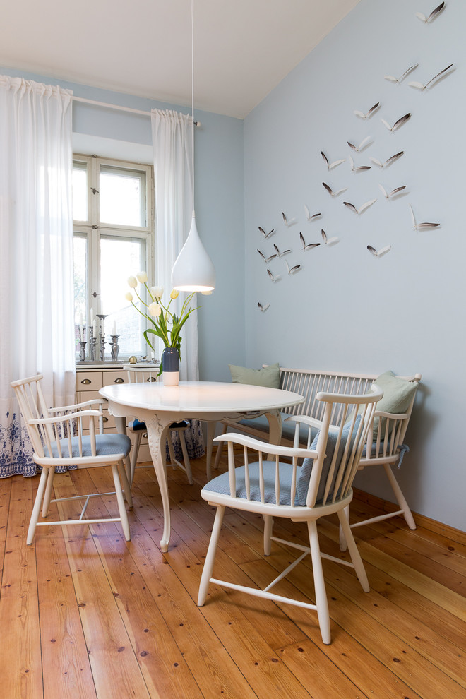 Cette photo montre une salle à manger chic de taille moyenne avec un mur bleu, un sol en bois brun et un sol marron.