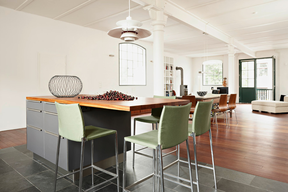 Aménagement d'une salle à manger ouverte sur le salon industrielle avec un mur blanc, un sol en bois brun et un sol gris.