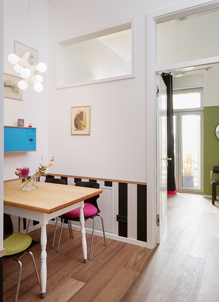 Kleine Moderne Wohnküche ohne Kamin mit hellem Holzboden, weißer Wandfarbe und braunem Boden in Düsseldorf