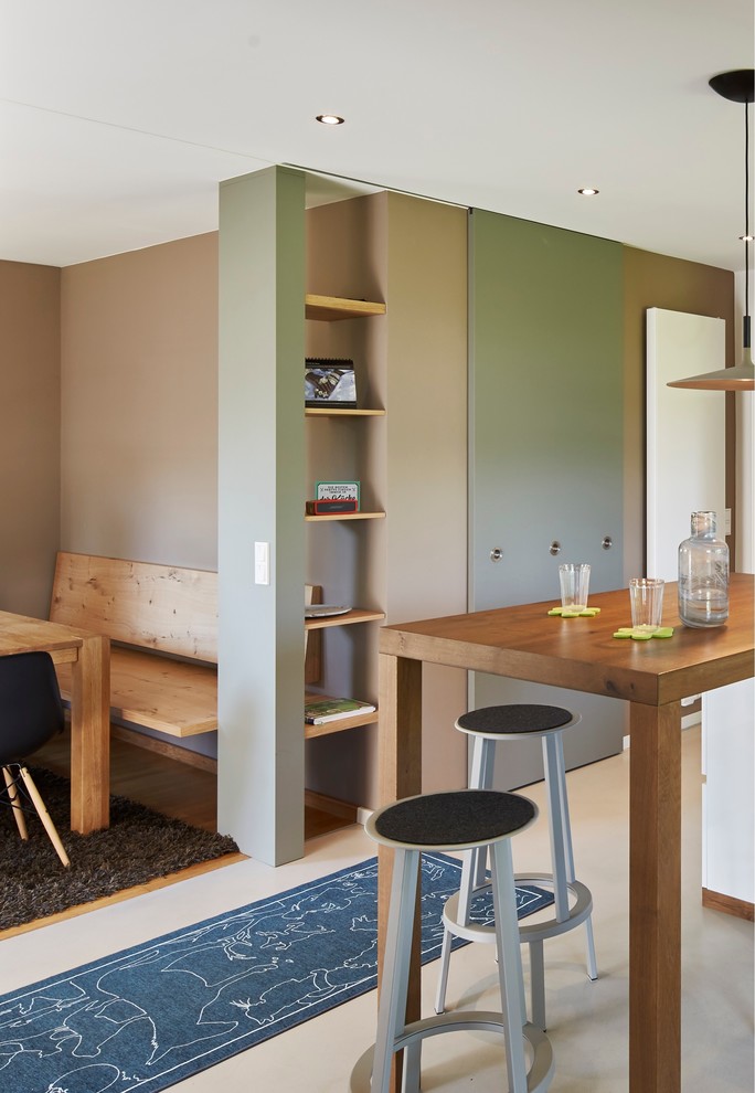 Réalisation d'une salle à manger ouverte sur le salon design avec un mur beige, parquet peint, un poêle à bois et un sol marron.
