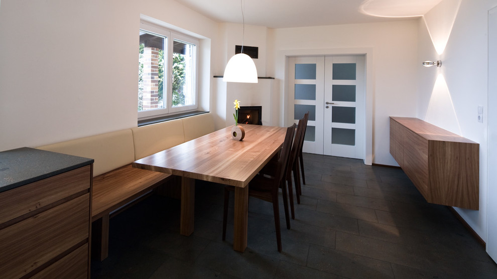 Immagine di una sala da pranzo aperta verso il soggiorno minimal di medie dimensioni con pareti bianche e pavimento grigio