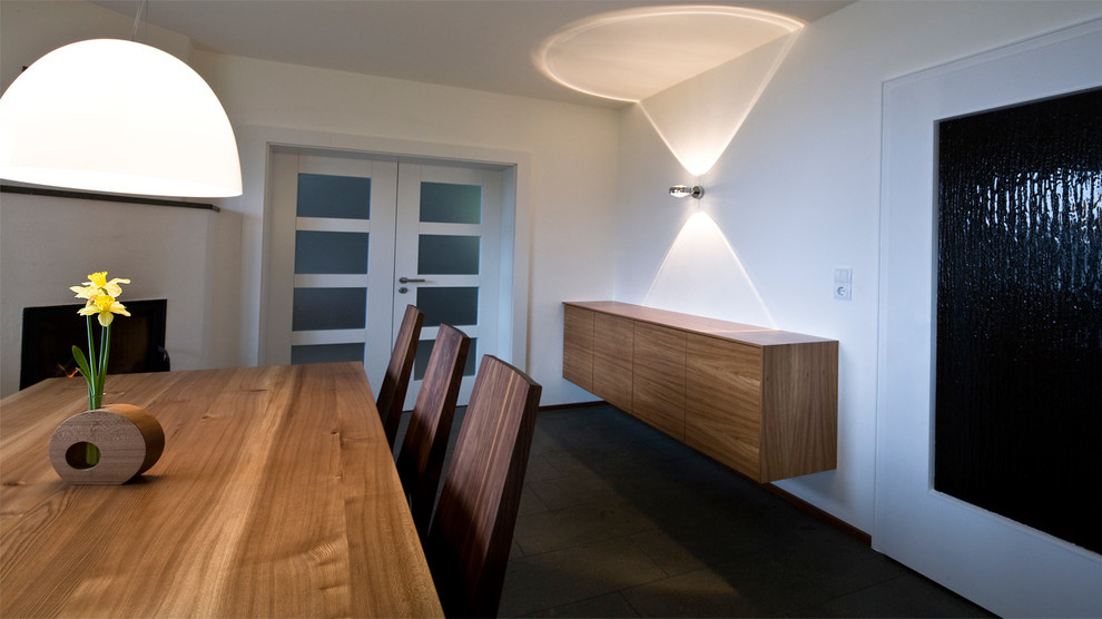 Aménagement d'une salle à manger ouverte sur le salon contemporaine de taille moyenne avec un mur blanc, tomettes au sol et un sol gris.