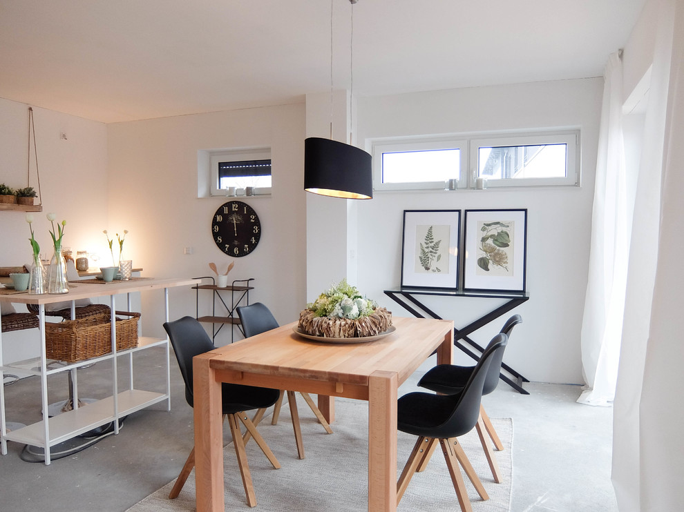 Immagine di una piccola sala da pranzo aperta verso il soggiorno scandinava con pareti bianche, pavimento in cemento e pavimento grigio