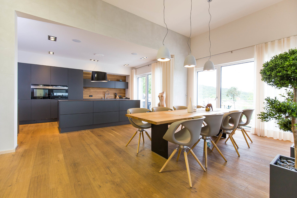 Immagine di una grande sala da pranzo aperta verso la cucina design con pareti bianche, pavimento in legno massello medio, nessun camino e pavimento marrone