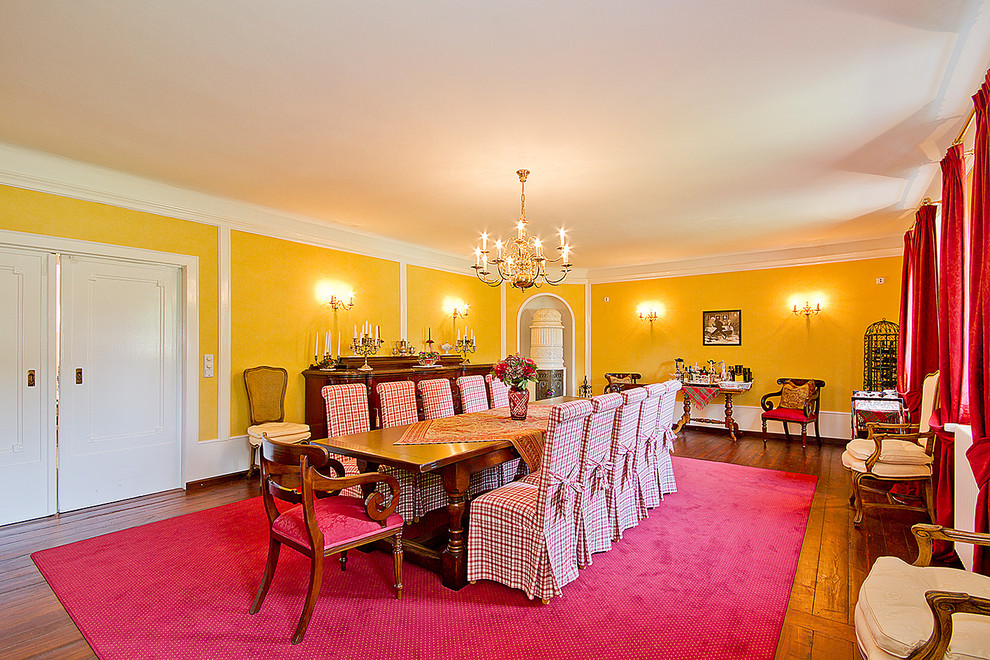 This is an example of an expansive country dining room in Other with yellow walls and dark hardwood flooring.