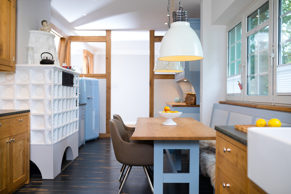 Стильный дизайн: кухня-столовая среднего размера в скандинавском стиле с темным паркетным полом, черным полом, белыми стенами, печью-буржуйкой и фасадом камина из плитки - последний тренд