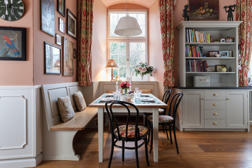 Idée de décoration pour une grande salle à manger ouverte sur le salon champêtre avec un mur rose et un sol en bois brun.