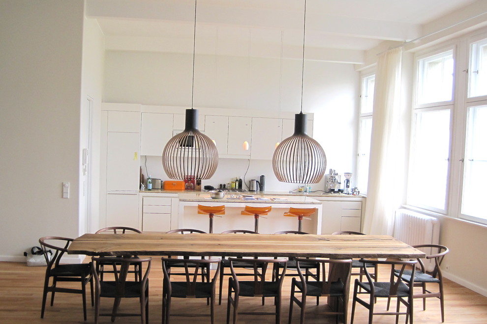 Foto di una sala da pranzo aperta verso la cucina minimal di medie dimensioni con pareti bianche e pavimento in legno massello medio